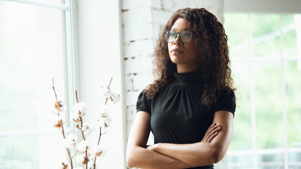Hands crossed. African-american businesswoman in office attire smiling, looks confident and serious, busy. Finance, business, equality and human rights concept. Beautiful young model, successful.
