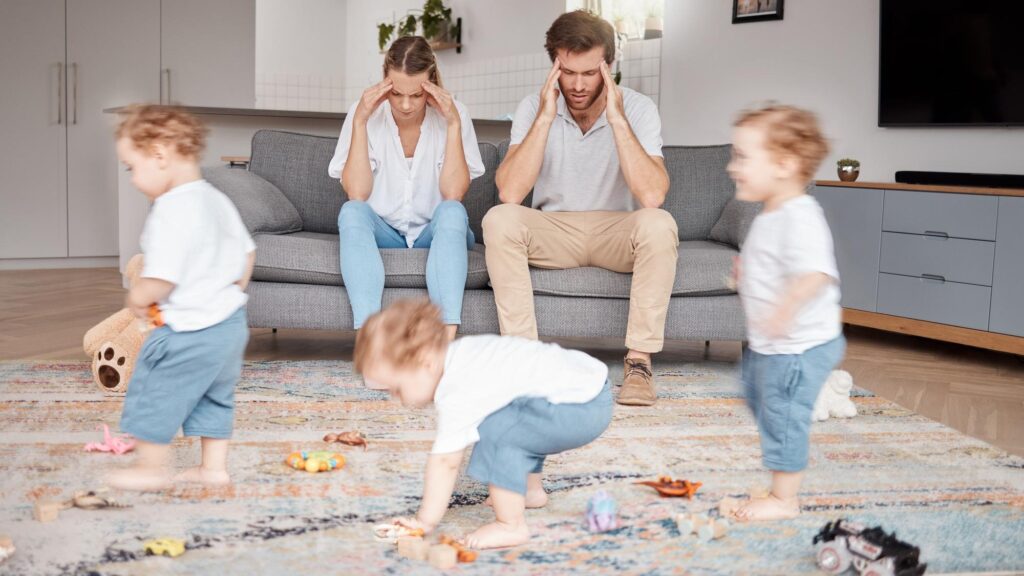 Parents stress and busy with an adhd child running around a home living room with energy or motion blur Family children and headache with a hyperactive kid in a lounge with a stressed mom and dad