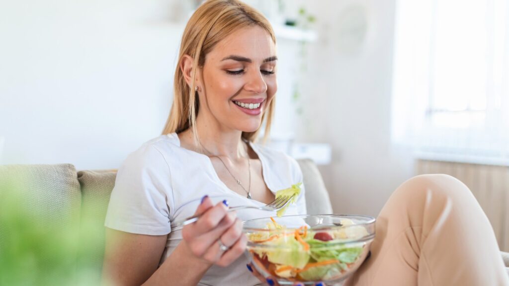 Portrait of attractive caucasian smiling woman eating salad. woman eating healthy salad with tomatoes cherry indoors Healthy lifestyle