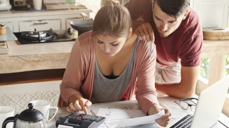 Family budget and finances concept. Young serious wife and husband doing accounts together at home