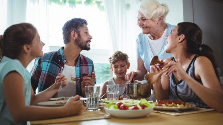 Elderly woman serving meal to her family
