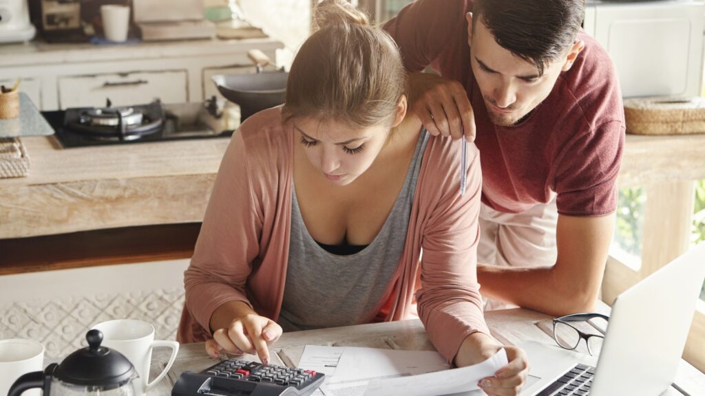 Family budget and finances concept. Young serious wife and husband doing accounts together at home