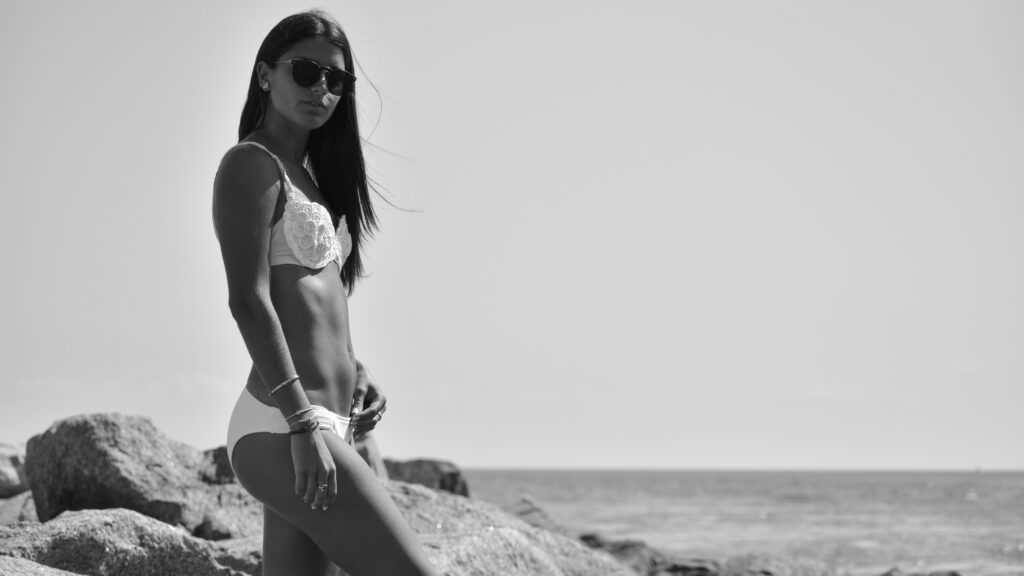 woman in bikini sitting on rock