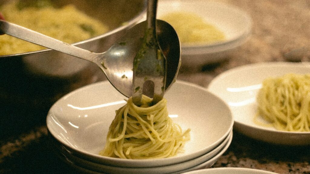 a person is spooning spaghetti into a bowl