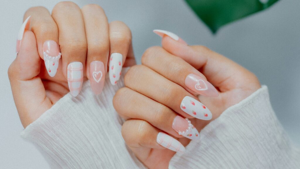 Woman's hands with white and pink heart-designed nails