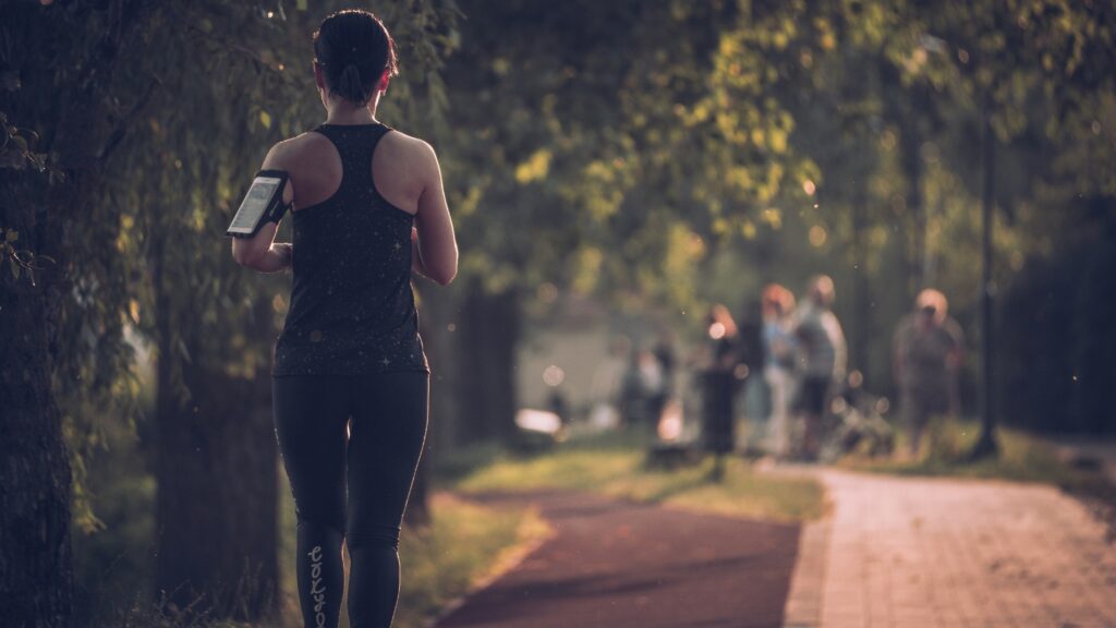 woman in black tank top and black pants walking on sidewalk during daytime
