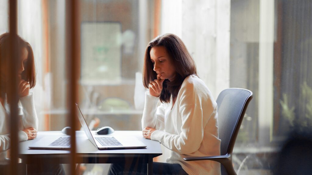 a woman sitting at a table with a laptop computer