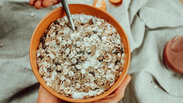 a person holding a bowl of oatmeal next to an orange