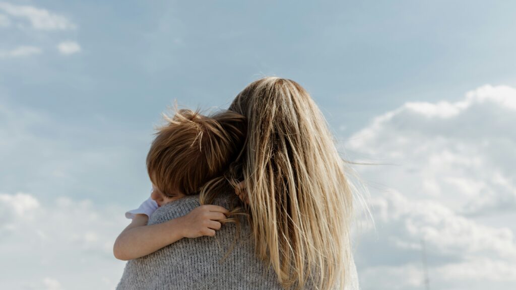 woman holding child from behind against cloudy sky