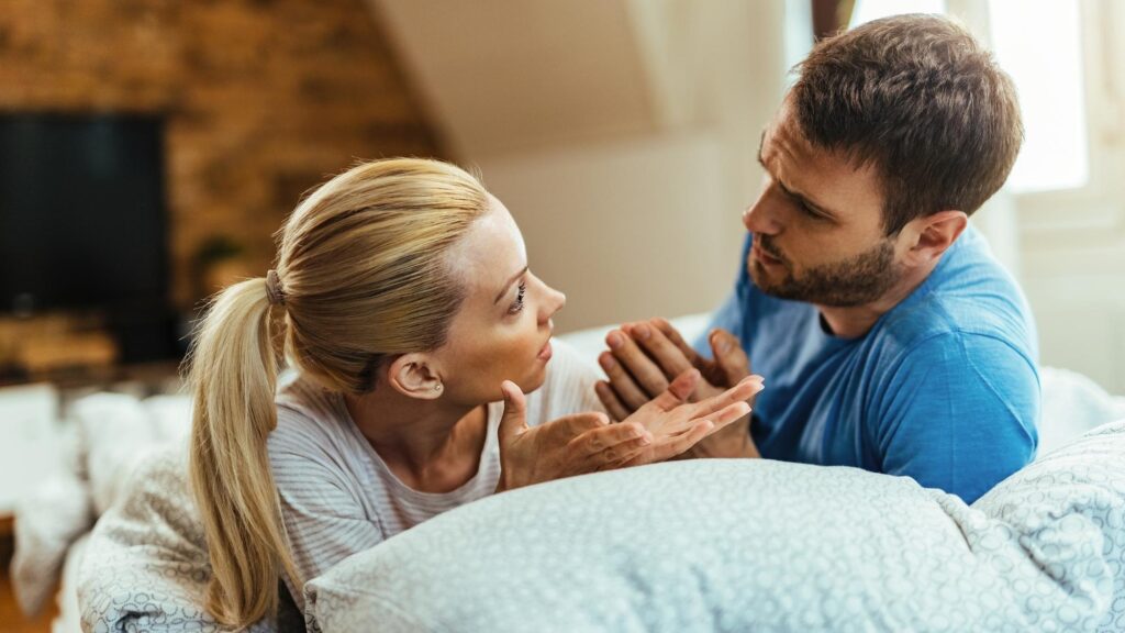Young couple talking while having relationship problems in bedroom