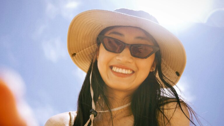 woman in black tank top wearing brown sun hat and black sunglasses