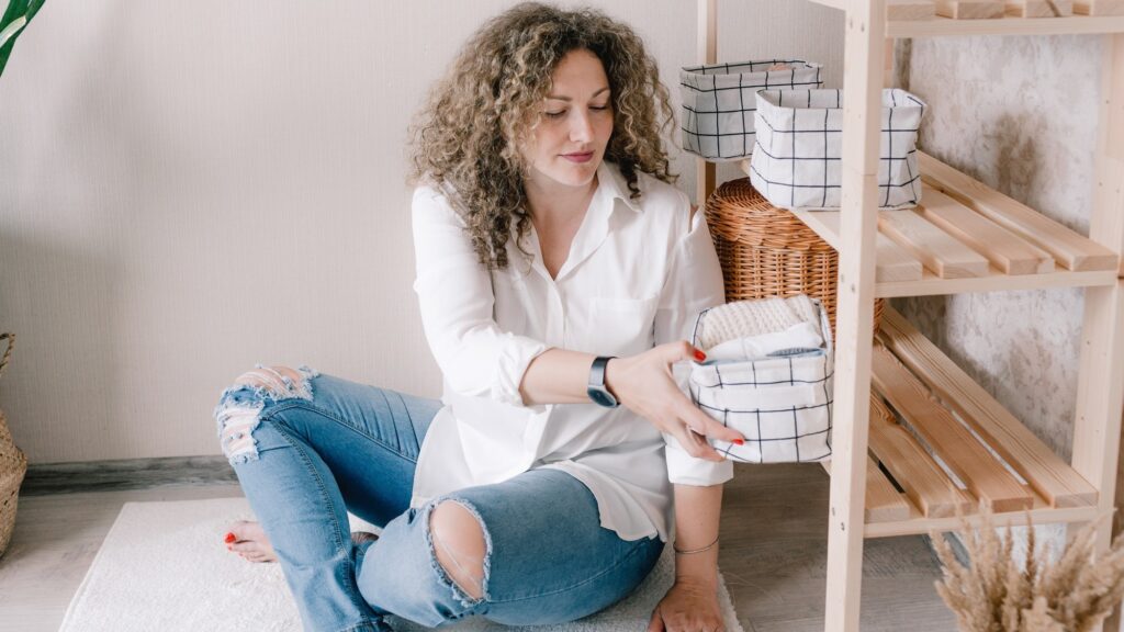 Portrait of a young woman in casual clothes beautifully putting things in containers and boxes. The concept of proper storage of accessories and underwear in the closet