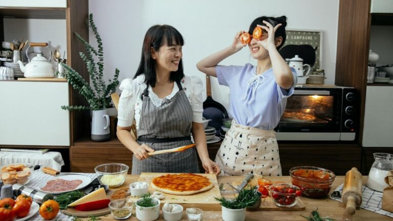 Happy Asian women putting sauce on pizza