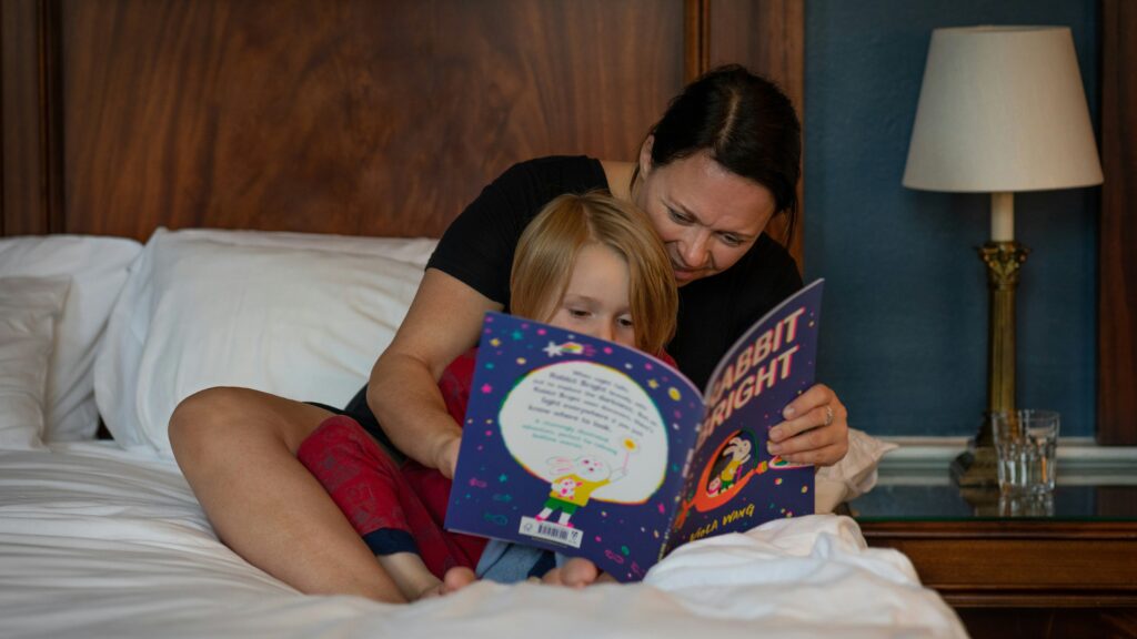 girl in red shirt lying on bed reading book