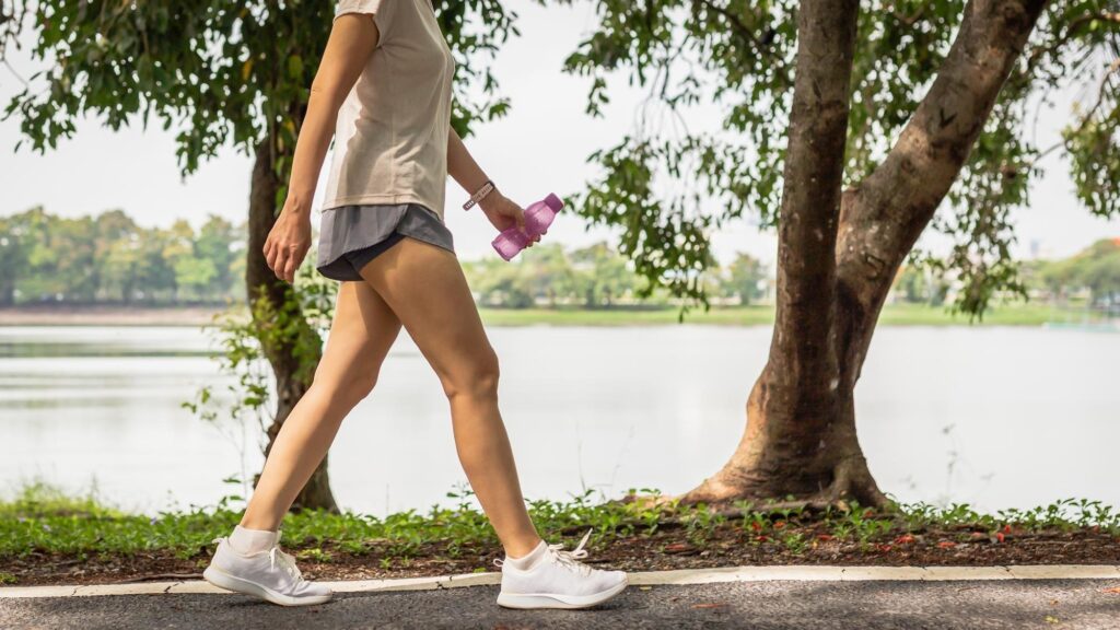 Woman walking in the park with bottle water in her hand health care concept