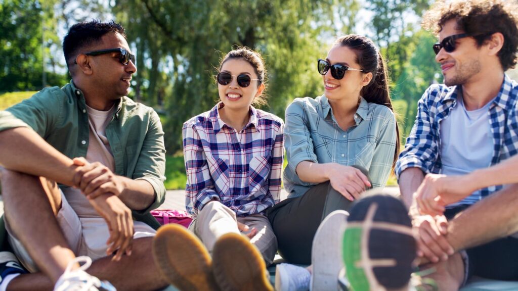 friends hanging out and talking outdoors in summer