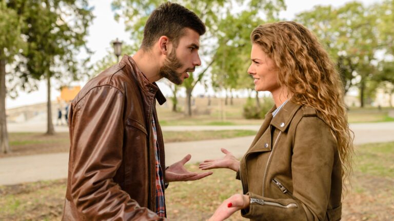 A couple having an argument outdoors, expressing frustration and conflict.