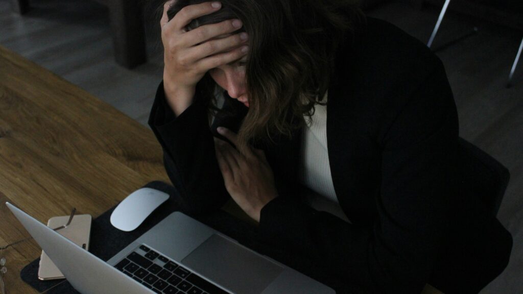 stressed woman with head in hands at laptop