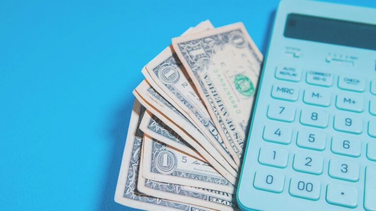 Us dollar bills and a calculator on blue background