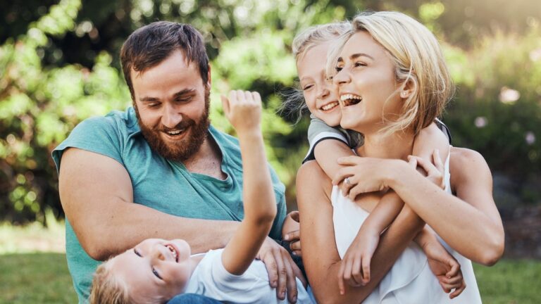 Family children and nature with playing mother kids and father in the park during summer laughing and having fun together Happy freedom and playful with a girl boy and parents sitting on grass