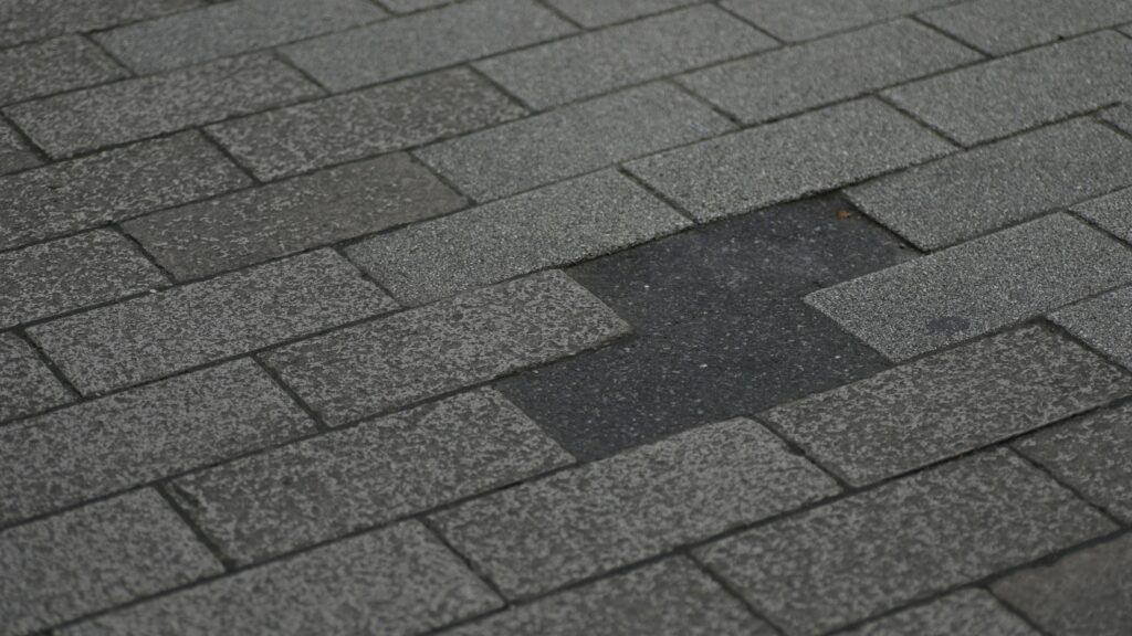 Damaged asphalt shingle roof with missing shingles.