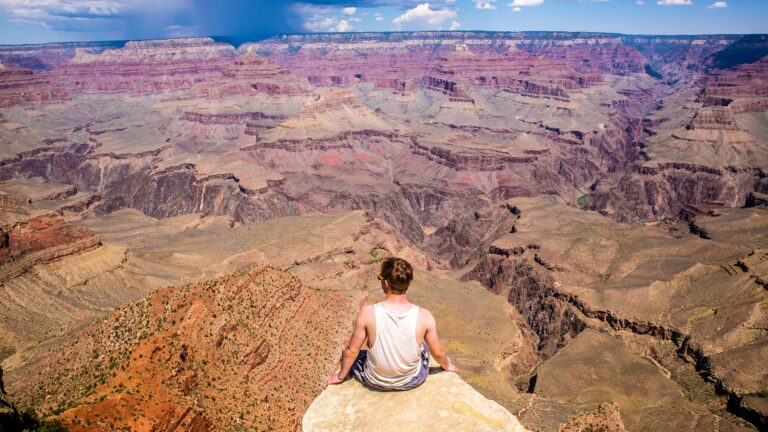 person sitting on cliff during daytime
