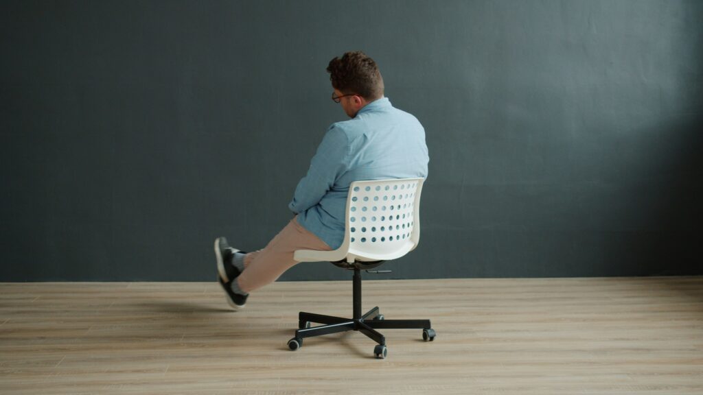Man sitting on office chair with legs crossed.