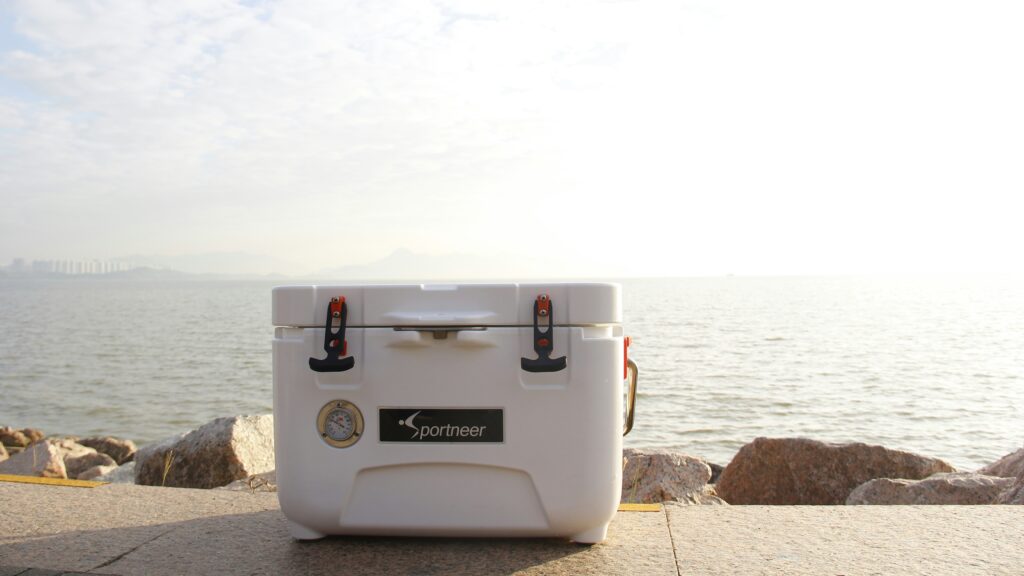 white cooler box on brown concrete pavement near body of water