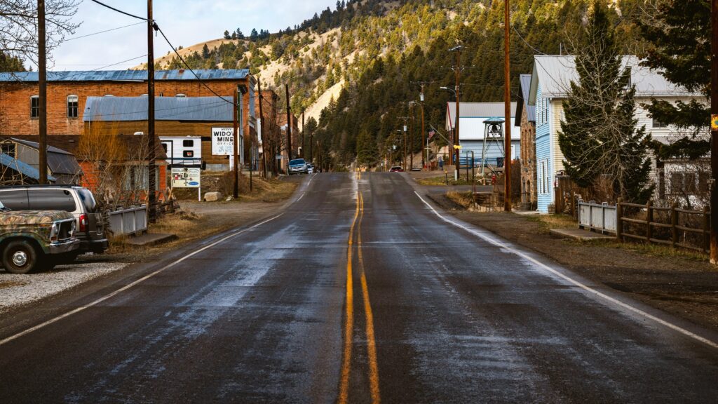 Empty road stretching through a rustic mountain village.