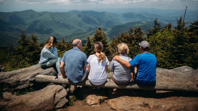 group of people sitting on rocks overlooking mountain