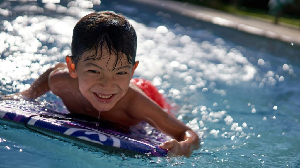 boy in pool smiling during daytime
