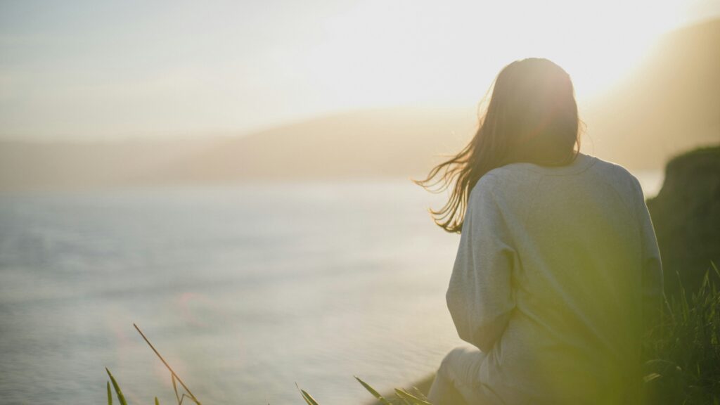 woman wearing gray long-sleeved shirt facing the sea