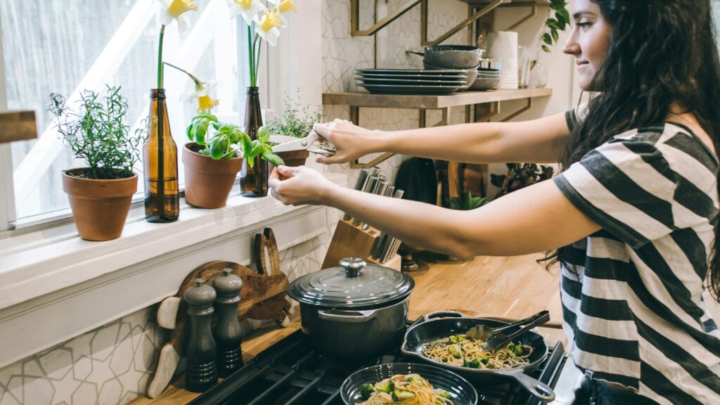 woman standing in front of cooking range holding flower's leaves