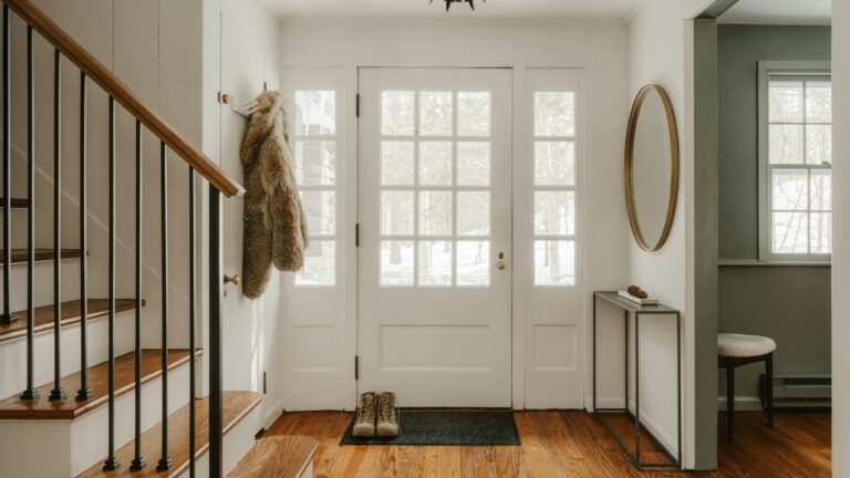 A cozy entryway with wooden stairs and a glass door.