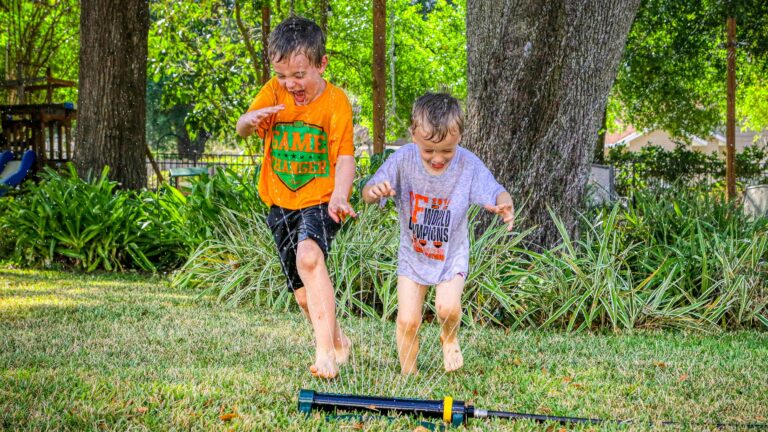two young boys playing a game of croquet in a yard