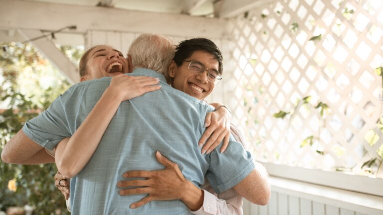 A diverse group shares a heartwarming hug indoors, radiating happiness and connection.