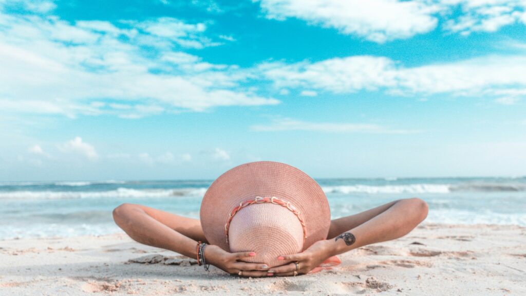 woman in brown sun hat lying on sand during daytime