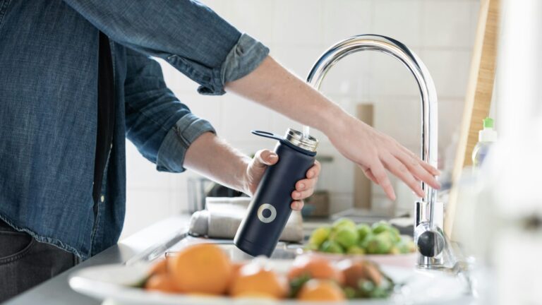 person in blue denim jacket holding stainless steel bottle
