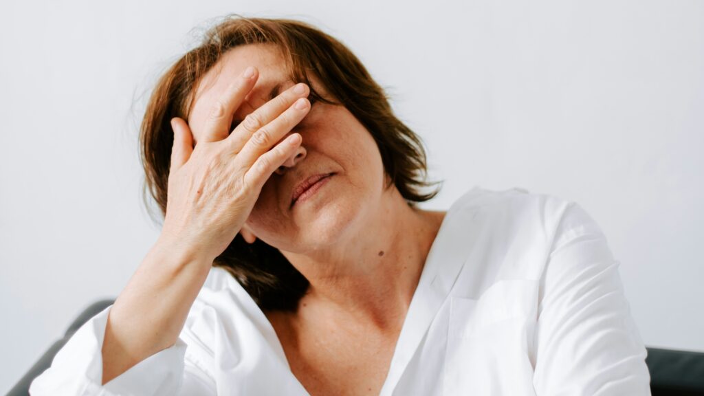 a woman sitting on a couch holding her hands to her face