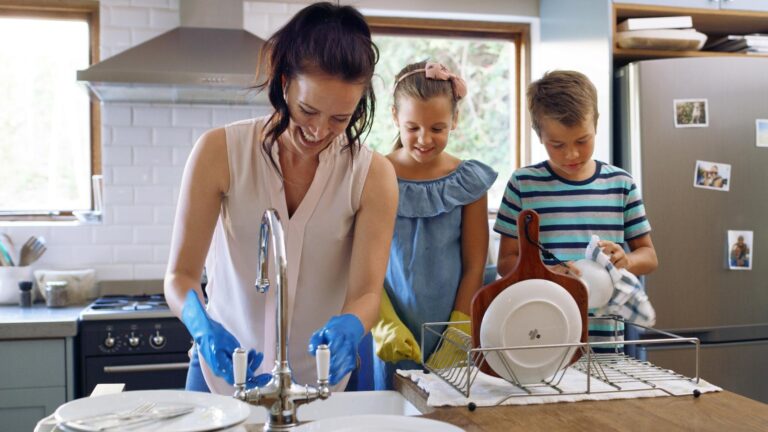 Mother kids and cleaning dishes for help learning and bonding with chores in the home Family happiness and mom with children in kitchen wash dirty plates teach maintenance and hygiene in house