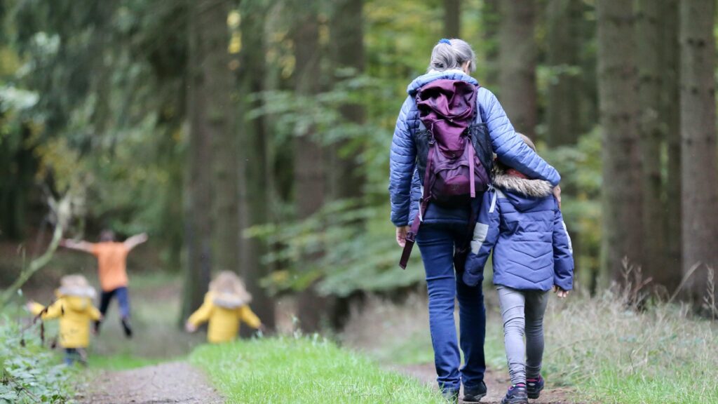 woman in blue denim jeans and black jacket walking with woman in green jacket