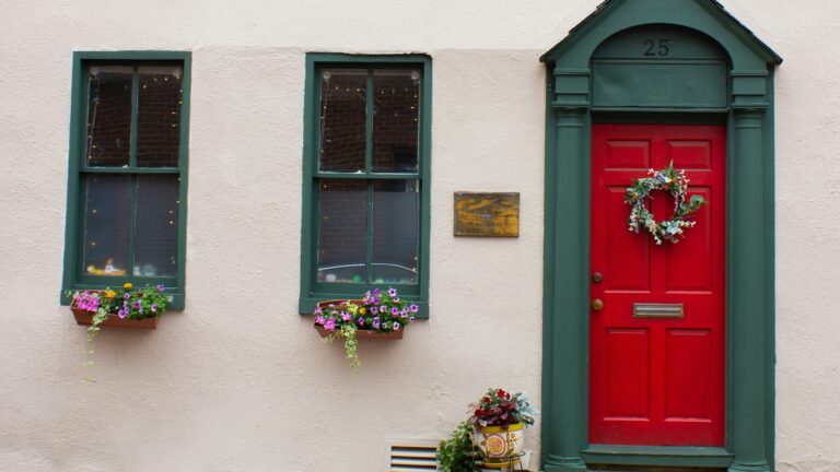a red door with two green windows and a bench in front of it