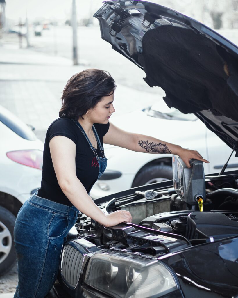 Woman adding oil to a car engine