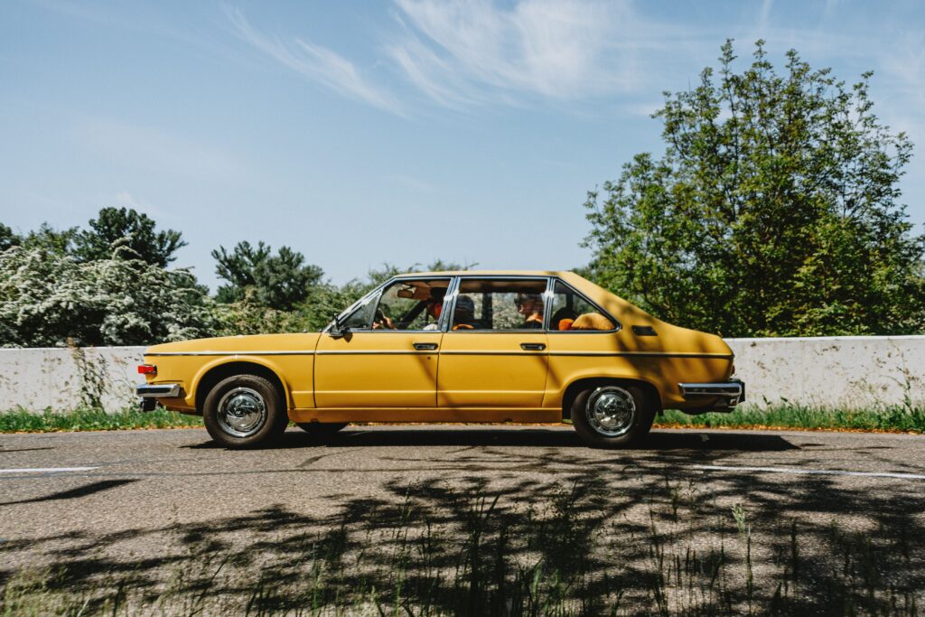 parents, kids on a road trip in old car