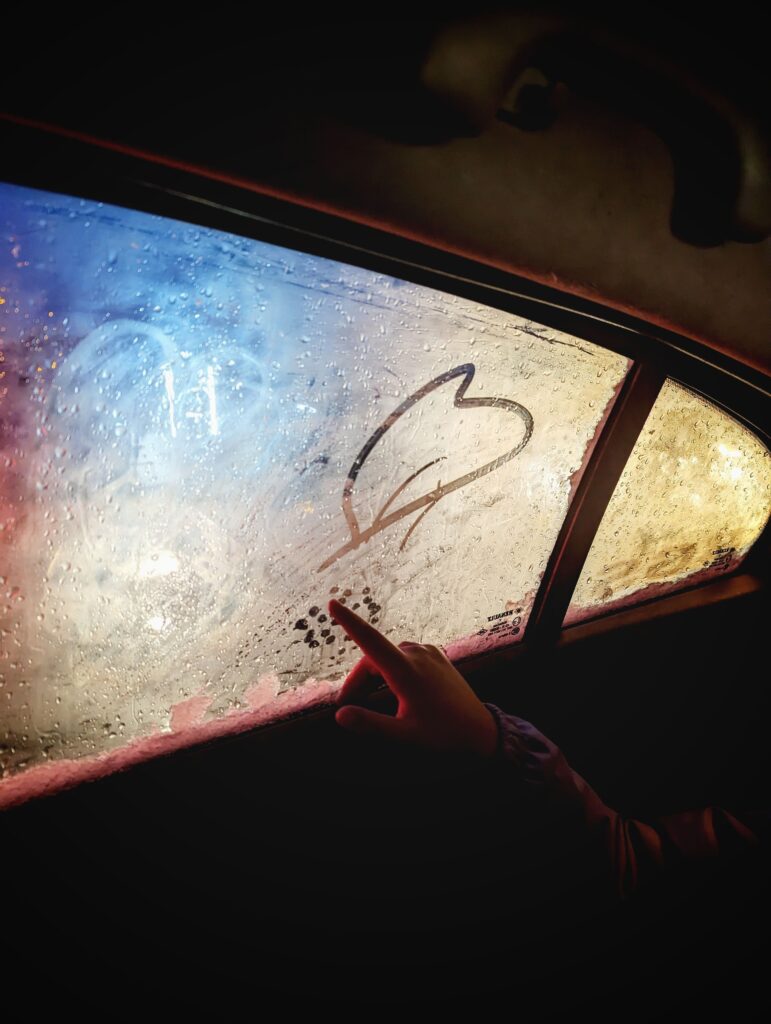 child writing on foggy car window