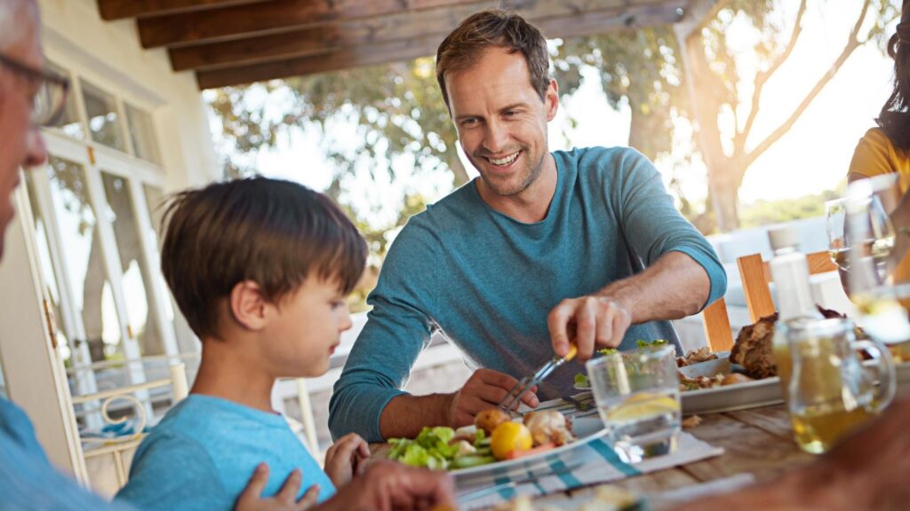 Family father and child with food for lunch supper and dinner meal at home together Celebration parents and children with dish for bonding relax and eating for nutrition health and wellness