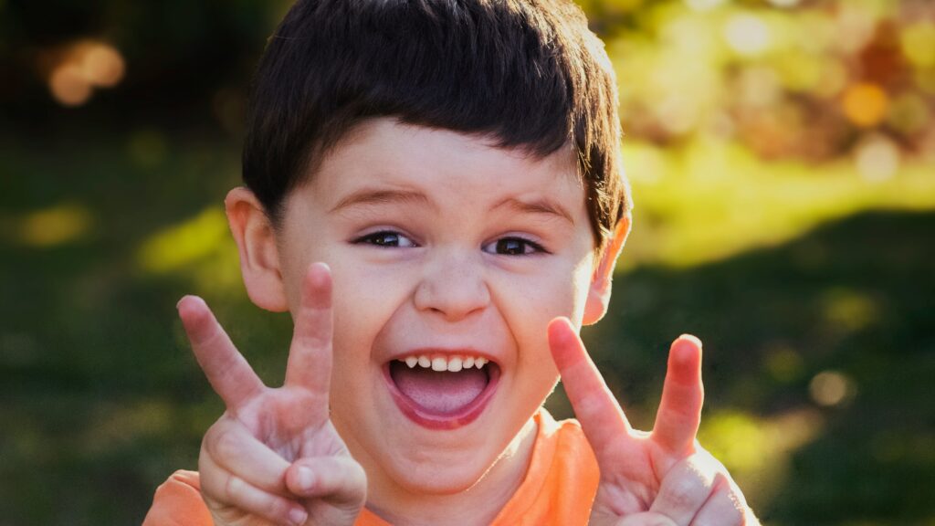 boy in orange crew neck shirt smiling