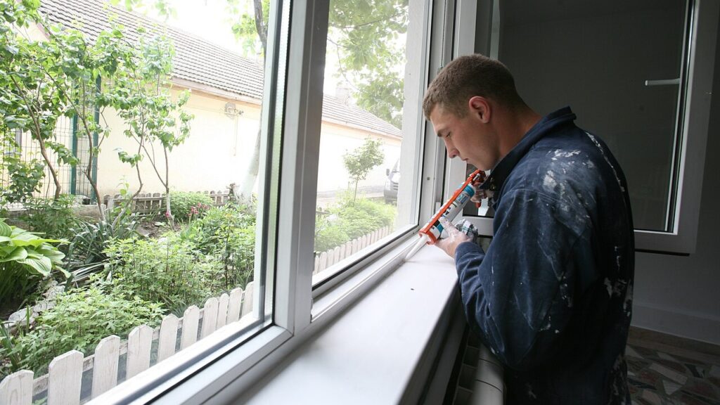 Lance Cpl. John Lamecker, a radio operator with 1st Tank Battalion, applies caulk to a window as part of a home refurbishment civil affairs project, May 19.