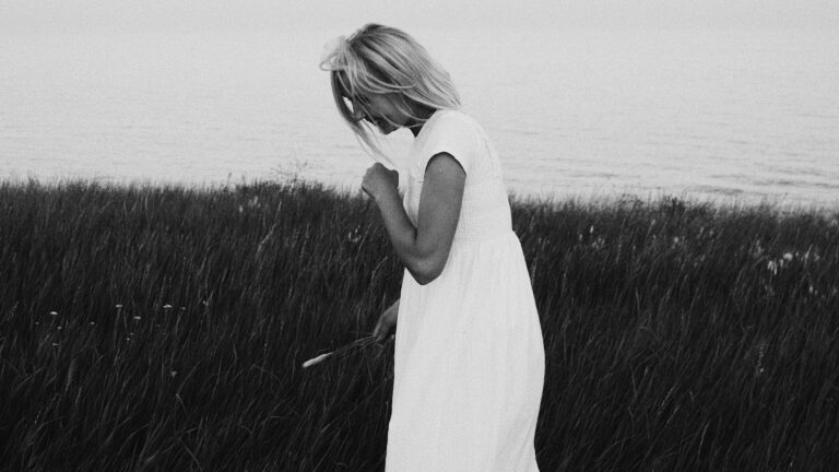 grayscale photography of woman wearing dress standing while looking down