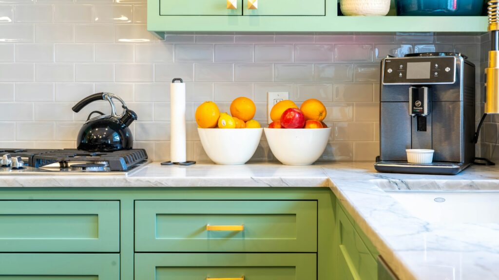 a kitchen with green cabinets and white counter tops